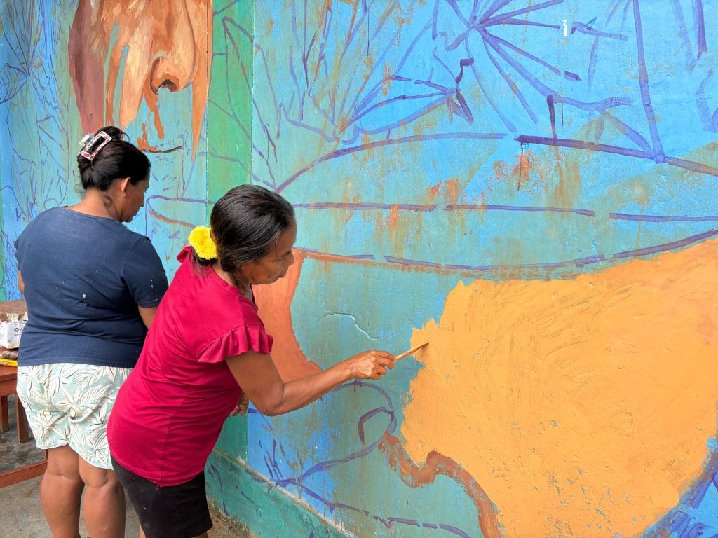 Mujeres maijuna pintando el mural