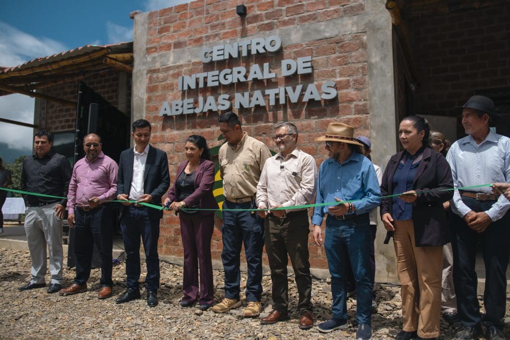 Group of people at a ribbon-cutting ceremony in front of a brick building with a sign that reads Centro Integral de Abejas Nativas.